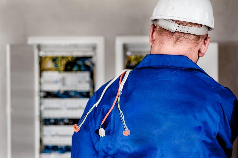 Electrician in blue coveralls working at residential breaker cabinets