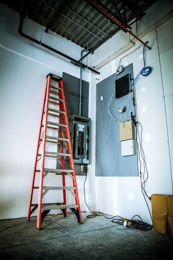 Commercial electrical room with panel and ladder mid-installation